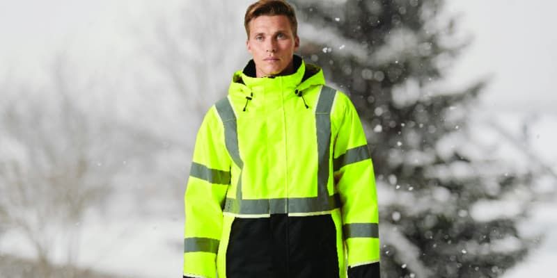 Male wearing yellow hi-vis coat on winter background